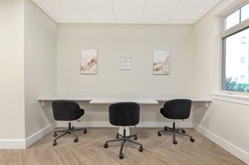 A conference room with a table and chairs and two paintings on the wall